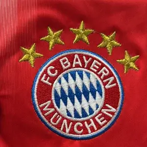 Detailed FC Bayern Munich crest with gold stars using high-density Custom Soccer Jersey Embroidery.